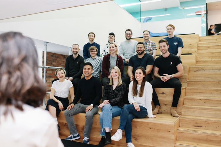 The Trainline design team sitting together on wooden steps