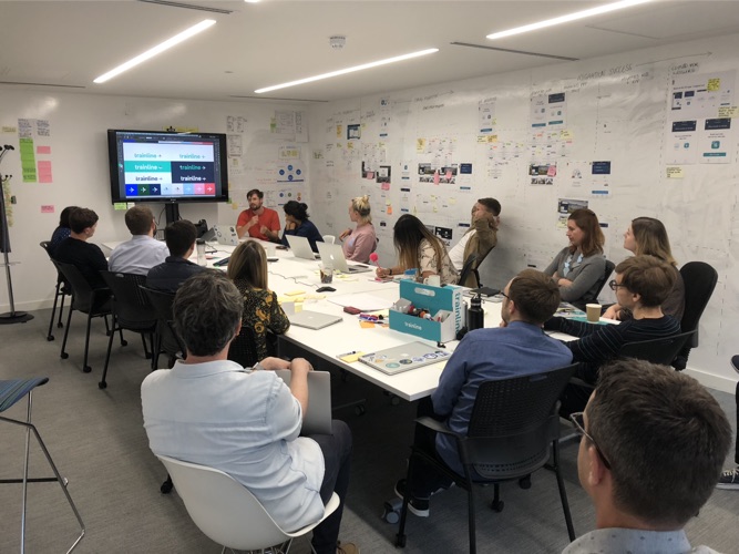 The design team in a workshop, with the new Trainline logo on screen